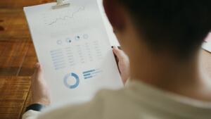 Analytics charts on a laptop beside a notebook